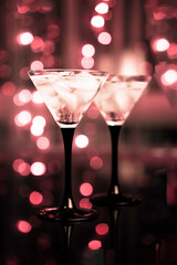 Two glasses of fresh cocktail with ice on black bokeh background.