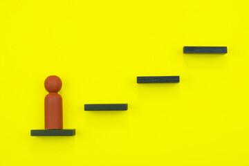 Leadership and career concept. Wooden figurine climbing up the steps.