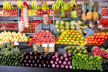 Fototapeta na wymiar Portrait of male and female young shop assistants working responsibly in fruit and vegetable shop