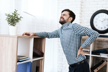 A man is bent and suffers severe back pain.