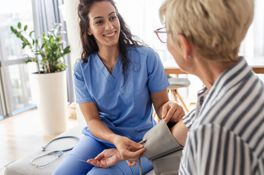 Female nurse measures blood pressure to senior woman while being in a home visit.