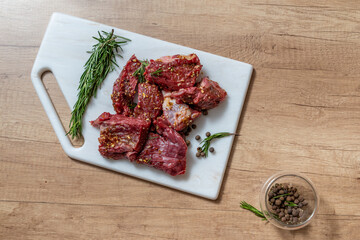 raw lamb chops with rosemary and pepper on marble board. preparing meat. marinated meat. beef. preparing food on kitchen. cooking. beef steak with vegetables