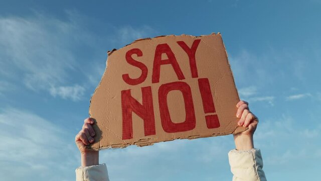 Say No! woman hands holding on cardboard background of blue sky sunset winter. Freedom. Worldwide protest. World riots.  Protests