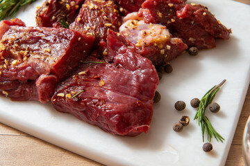 raw lamb chops with rosemary and pepper on marble board. preparing meat. marinated meat. beef. preparing food on kitchen. cooking. beef steak with vegetables