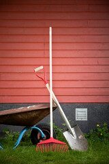 Garden tools outdoors on a red wooden wall.