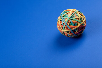 Studio photo of one rubber band ball on colorful blue background.