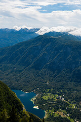 Fototapeta na wymiar Standing on top of the mountain Planina Blato in the Triglav National Park in Slovenia looking down on Lake Bohinj and the village Ukanc on sunny day with clouds