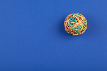 Studio photo of one rubber band ball on colorful blue background.