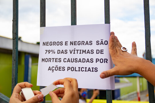 Detalhe de m&atilde;os colando cartaz em grade de port&atilde;o. Foto feita em manifesta&ccedil;&atilde;o contra o racismo na cidade de Goi&acirc;nia.