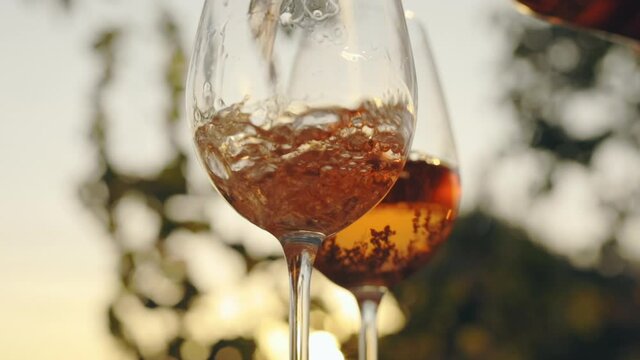 Pouring rose wine into a glass at sunset