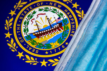 Facial Mask on Flag and seal of New Hampshire. Several communities in NH require that face coverings be worn in public, effective November 20 in 2020.