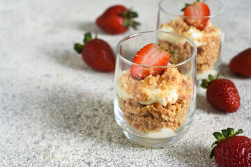 Dessert with crumbs, cream and strawberries. Cheesecake in a glass.