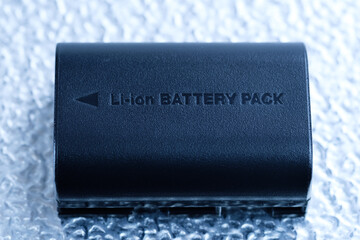 Eine schwarze wiederaufladbare Lithium-Batterie (Li-ion Battery / Akku) liegt auf einem...