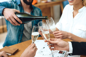 People sit at table and drink champagne together.