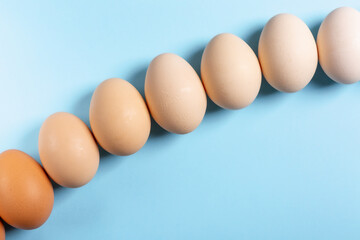 Raw chicken eggs on light blue background. Flat lay, copy space, top view.