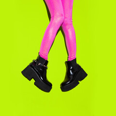 Fashion legs in platform party boots and pink leggins on minimal yellow background. Stylish...