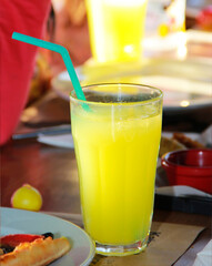 yellow orange drink in a glass glass with a straw