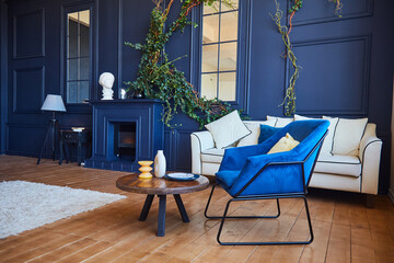 Modern interior of a spacious living room with contrasting blue walls and wooden floors, a blue...