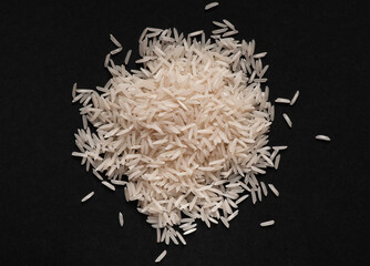 Heap of white basmati rice on black background.  Food design. Flat lay.