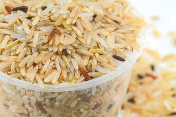 Macro mix organic brown rice grains in measuring rice cup, view from above.