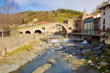 View of the 12th century New Bridge one morning in the middle of autumn where some people are walking. Camprodon, Catalonia, Spain.