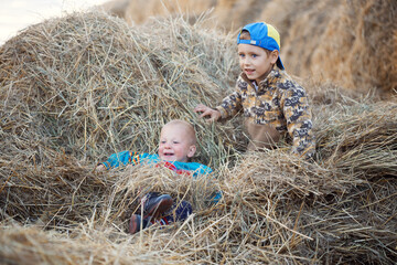 children play with a stack of straw at sunset