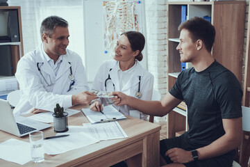 Obraz premium Male athlete bribes doctors in the office. 