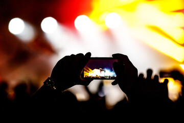 Silhouette of hands using camera phone to take pictures and videos at live concert