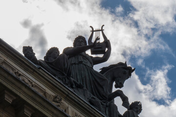 
statue playing harp backlit with cloud sky, denmark, copenague