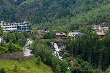 houses built under the mountain, river flows into fjord, norway