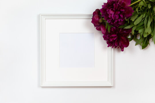 Square white frame with bouquet of peonies on white background, copy space. Flat lay or side view, minimal style mockup. For gift shop, social media, website design