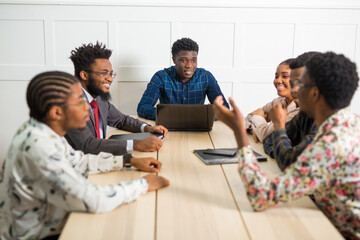 team of young african people working in office at table with laptop