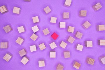 Fototapeta na wymiar wooden blocks on a purple background with one painted red. Concept of 