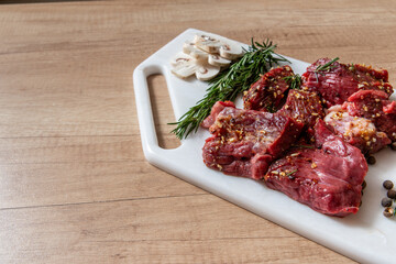 raw lamb chops with rosemary and pepper on marble board. preparing meat. marinated meat. beef. preparing food on kitchen. cooking. beef steak with vegetables