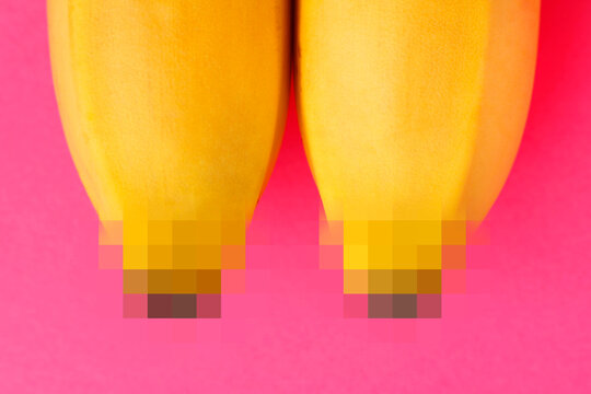 Two ripe bananas as a concept of female boobs on a pink background. Mosaic nipple censorship. Erotic fruits.