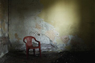 Lost chair in a lost place. Red broken walls decay destroyed dirt wooden floor sitting fear alone...