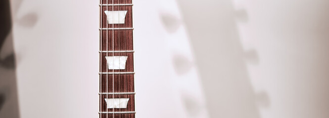 Beautiful, new, brown and white electric guitar close-up. Abstract photo for a website header,...