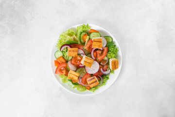 Traditional Middle Eastern vegetarian salad fattoush. Lebanese cuisine recipe. Fresh vegetables, cherry, lettuce, toasted pita bread. White concrete background. Healthy meal, top view. Copy space