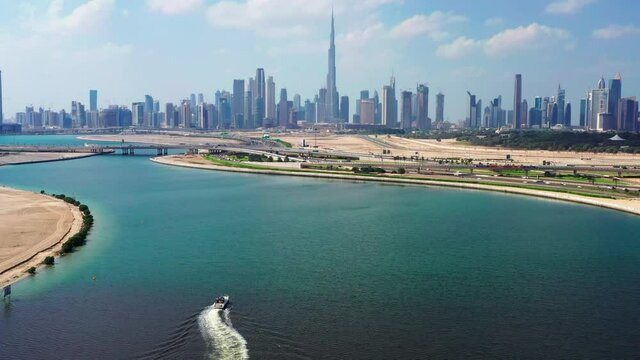 Panoramic aerial view of Dubai city skyline on cloudy day moving over man made lake
