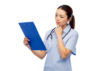 medicine, profession and healthcare concept - pensive asian female doctor or nurse in blue uniform with clipboard and pen over white background