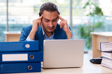 Young male employee and too much work in the office