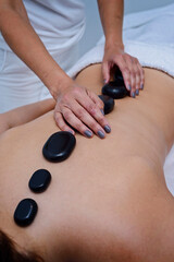 Obraz na płótnie Canvas Masseuse putting hot stones on the back of pacient.Concept of beauty and wellness