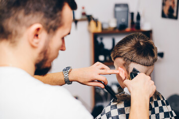 Fototapeta premium Hairdresser barbershop parihopher strechot small boy sitting on a chair