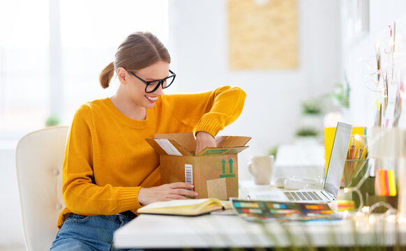 Smiling woman unpacking parcel at home.