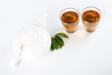 Green tea leaf and glass cup of black tea isolated on white background
