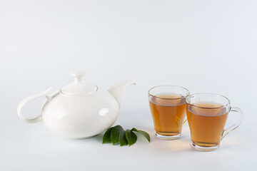 Green tea leaf and glass cup of black tea isolated on white background
