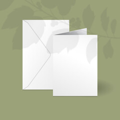 White vertical greeting card and envelope mockup template with holly berry branch with leaves overlay shadow.