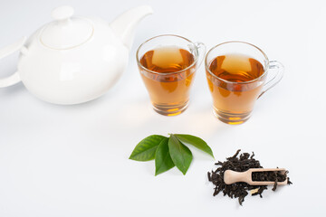 Green tea leaf and glass cup of black tea isolated on white background
