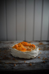 Low light photo of home made carrot cake with cream cheese frosting, fresh oranges and caramel crumbles