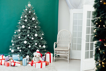Christmas tree with presents underneath in living room. White room.